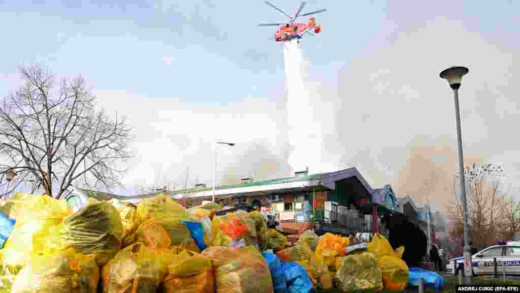 Prodavci spašavaju svoju robu dok helikopter ispušta vodu na požar u &quot;Kineskom tržnom centru&quot; u Beogradu 24. januara.