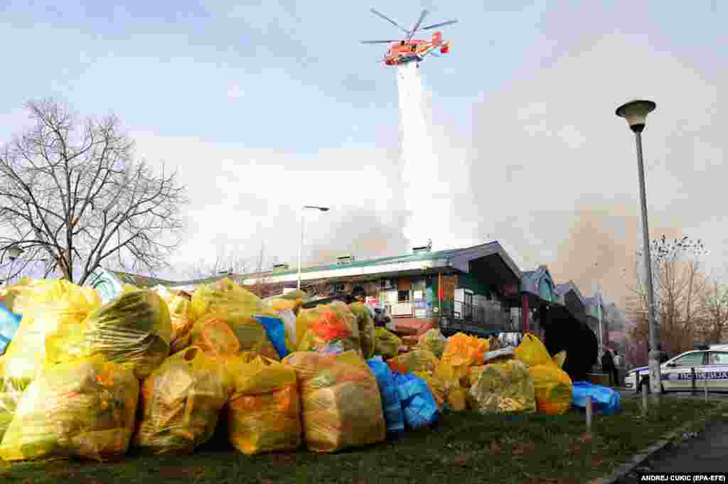 Vendors salvage their merchandise as a helicopter drops water on a fire at a Chinese bazaar in Belgrade on January 24.