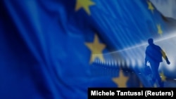 Flamuri i Bashkimit Evropian shihet në prapavijë teksa një njeri ecën. Fotografi ilustruese nga arkivi.