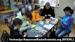 Жінки-вимушені переселенки разом зі своїми дітьми під час заняття з арт-терапії роблять обереги для українських бійців