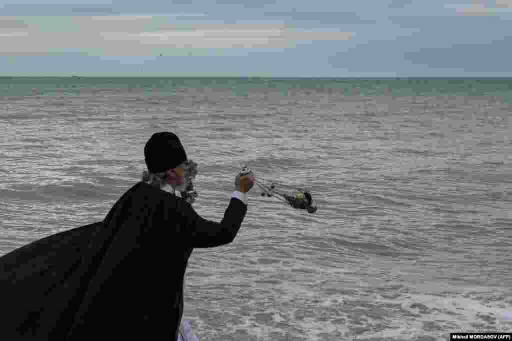 Along the Black Sea coast near Sochi, Russia, a priest is seen blessing the water before he jumps in.