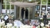 Surrounded by tributes to victims of two mass shootings last week, police officers stand guard outside a school on May 8.