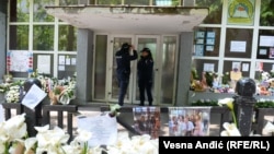 Surrounded by tributes to victims of two mass shootings last week, police officers stand guard outside a school on May 8.