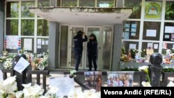 Të rrethuar nga homazhet për viktimat e dy të shtënave masive në Serbi, dy police qëndrojnë roje jashtë një shkolle më 8 maj 2023.