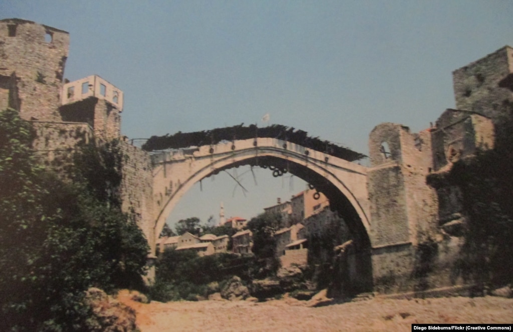 Ky imazh i marrë në gusht të vitit 1993 është një nga fotot e fundit të bëra nga Ura origjinale e Mostarit, e njohur në vend si "Stari Most". Pavarësisht se ishte e mbështjellë me goma dhe e mbuluar me dërrasa druri, ura ra në lumin Neretva pas një breshëri sulmesh nga forcat etnike kroate në nëntor të vitit 1993.