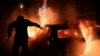 Një zjarrfikës duke shuar flakët e një makine të ndezur nga protestuesit në Nanterre të Francës, më 2 korrik 2023.