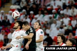 Tajikistan defender Zoir Dzhuraboyev (No. 2) and UAE's forward Caio Canedo (No. 11) vie for a header on January 28.