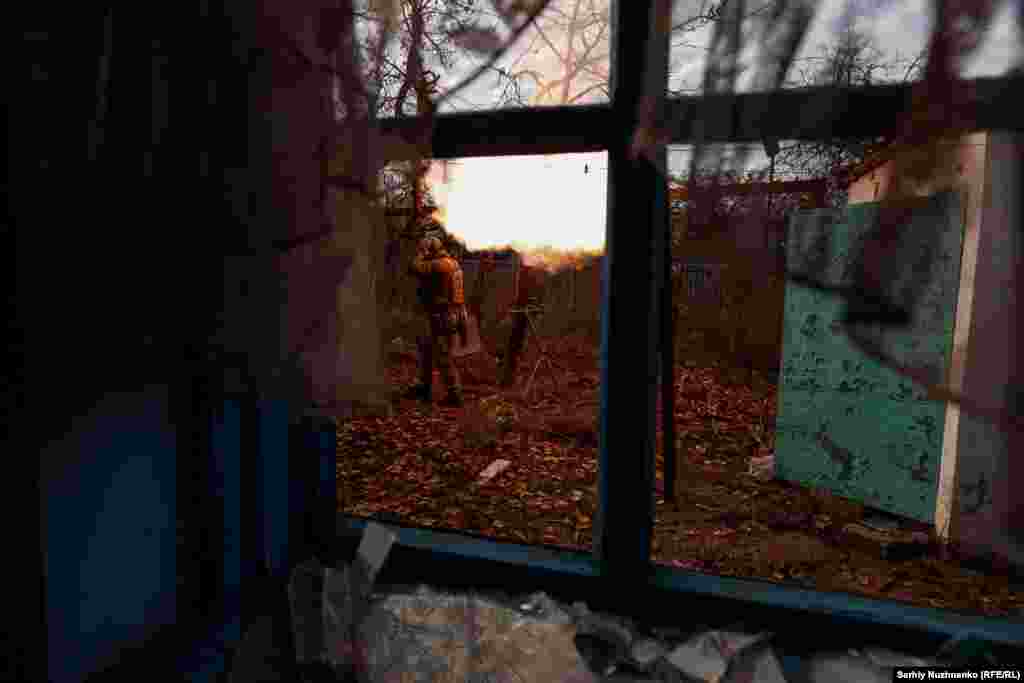 A view through a broken window shows Ukrainian soldiers firing on Russian positions. The General Staff of Ukraine&#39;s military&nbsp;said&nbsp;early on November 13 that Kyiv&#39;s forces had fought more than&nbsp;70 close-quarter battles in the Kupyansk, Bakhmut, and Avdiyivka directions.