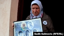 Nura Mustafić ispred porodične kuće sa fotografijama ubijenih sinova i muža.