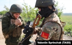 A Russian soldier wears a stylized Soviet flag emblazoned with the letters "USSR," near Avdiyivka in June.