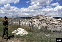 A Norwegian KFOR soldier photographs the ruins of an Orthodox church on the outskirts of Pristina that was destroyed by an explosion in July 2000.