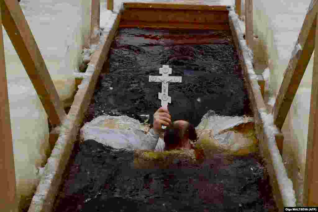 An Orthodox priest plunges into the icy waters of a lake during the celebration of the Epiphany holiday in the village of Orlino, Leningrad region, Russia.