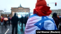 Učesnik protesta ogrnut izraleskom zastavom, Berlin, 10. decembar 2023.