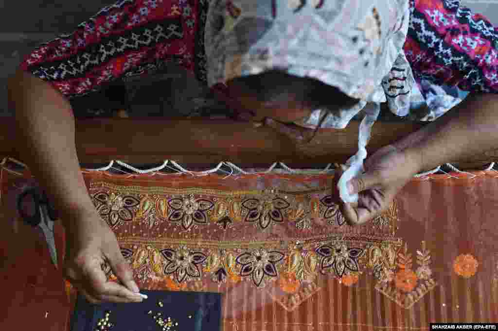 A woman handcrafts embroidery on clothing at her home in Karachi, Pakistan.