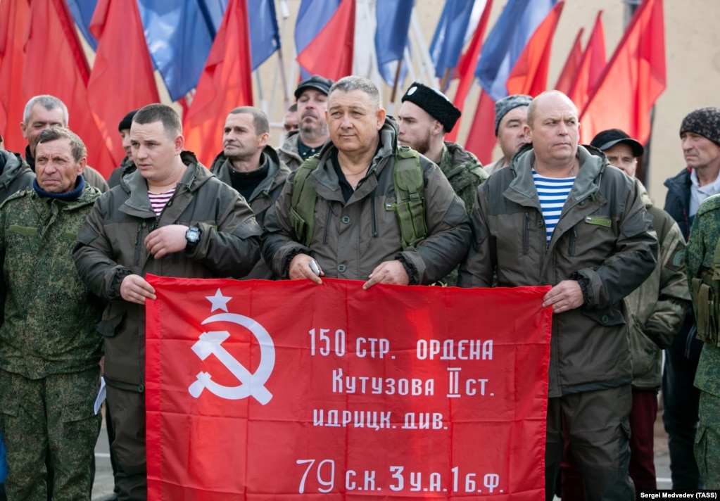Coscritti russi e volontari mobilitati sventolano la bandiera della vittoria sovietica mentre si preparano a partire per il fronte a Orenburg, in Russia, nell'ottobre 2022.