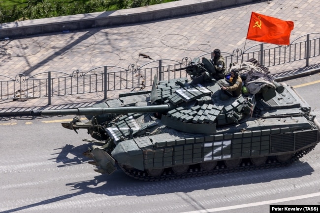 Російський танк під прапором неіснуючого СРСР в'їжджає в Маріуполь. 24 лютого 2022 року. Початок широкомасштабного вторгнення Росії в Україну