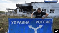 RUSSIA – Ukrainian historian Yuri Savchuk, head of the Kyiv-based Ukrainian WWII history museum, carries a road sign in Sudzha, Kursk region, Russia, August 16, 2024