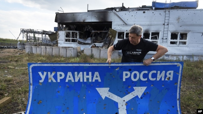 RUSSIA – Ukrainian historian Yuri Savchuk, head of the Kyiv-based Ukrainian WWII history museum, carries a road sign in Sudzha, Kursk region, Russia, August 16, 2024