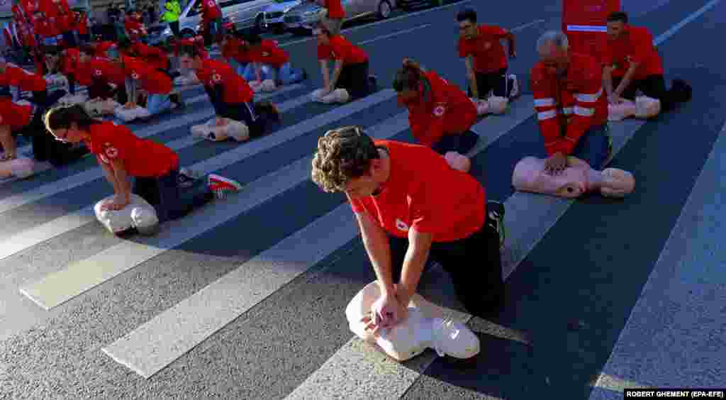 Voluntari români execută manevre de resuscitare pe manechine medicale în timpul unui flashmob organizat pe o trecere de pietoni din centrul Bucureștiului, pe 16 octombrie, pentru a marca Ziua Mondială a Resuscitării.