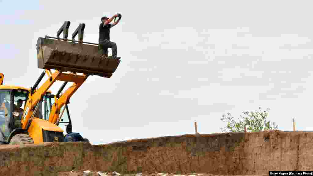 An archaeologist uses an excavator to take a picture from high above a tumuli. The photographing of artifacts and their position in the grave site can reveal information about the time period from which they originated.