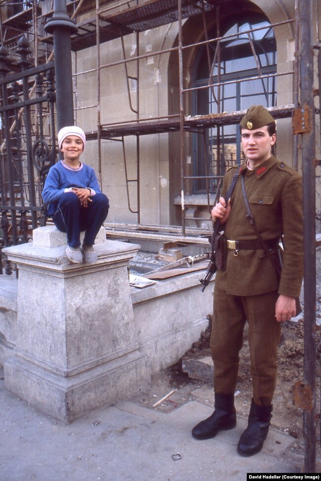 Një ushtar qëndron pranë një vajze të vogël në Bukuresht në marsin e vitit 1990, vetëm tre muaj pas revolucionit të vitit 1989.