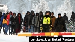 Finnish border guards escort would-be migrants at the border with Russia at Salla in northern Finland on November 23.