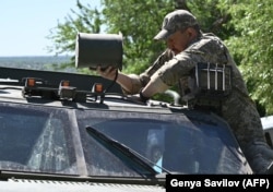 Un soldat ucrainean montează un dispozitiv de bruiere a dronelor pe un vehicul blindat în regiunea Donețk, aprilie 2024.