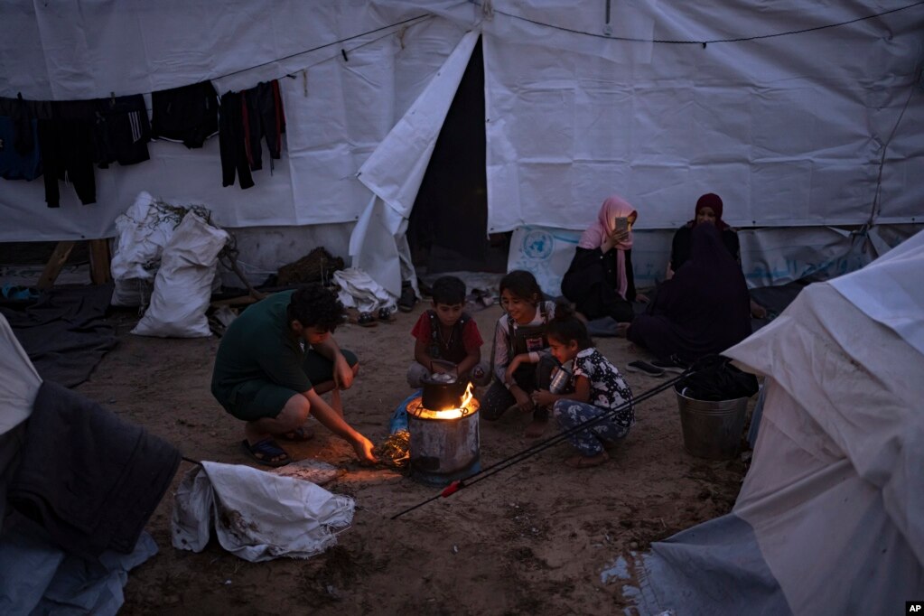 Palestinezët e zhvendosur në një kamp me tenda të siguruara nga UNDP-ja në Han Junis shihen duke zier ushqim në një zjarr në ambient të hapur.