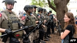 Студентка гледа тексаски войници, докато студенти протестират срещу войната между Израел и Хамас в кампуса на Тексаския университет в Остин.