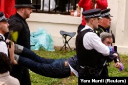 Ofițeri de poliție rețin un membru al mișcării „Just Stop Oil”, la ceremonia de încoronare a regelui Charles al III-lea, în Londra, Marea Britanie, 6 mai 2023.