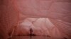 A visitor walks through a part of the National Gallery of Kosovo covered in an oversized duvet as part of an art exhibition titled Day Into Night, Night Into Year, in Pristina.