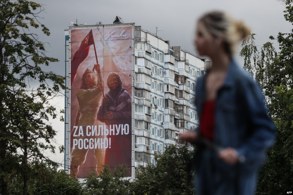 Uno striscione affisso in un condominio di Mosca a luglio mostra donne che sventolano la bandiera sovietica.  Sull'enorme poster si legge: "Per una Russia forte!".