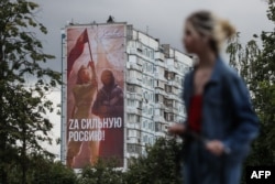 Un banner pe un bloc de apartamente din Moscova, în iulie, înfățișează femei arborând steagul sovietic. Pe uriașul afiș scrie: „Pentru o Rusie puternică!".