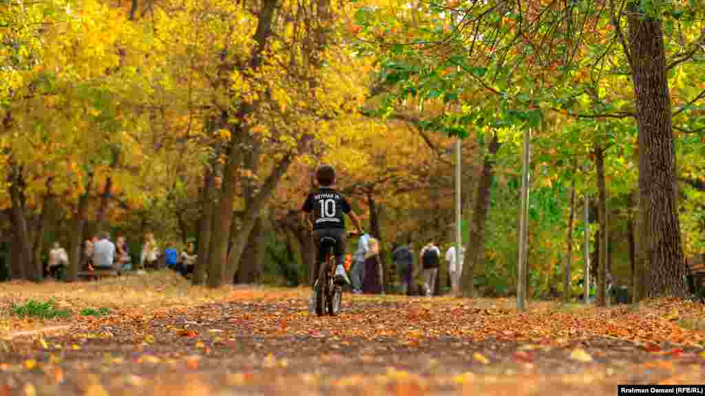 Un băiat merge cu bicicleta într-un parc din capitala kosovară, Priștina.