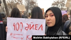 Участница митинга в Алматы держит плакат с надписью: «Кровь 400 женщин» с отсылкой на статистику о гибели женщин от бытового насилия. 8 марта 2023 года