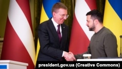 Latvian President Edgars Rinkevics (left) and Ukrainian counterpart Volodymyr Zelenskiy shake hands in Kyiv on November 24.