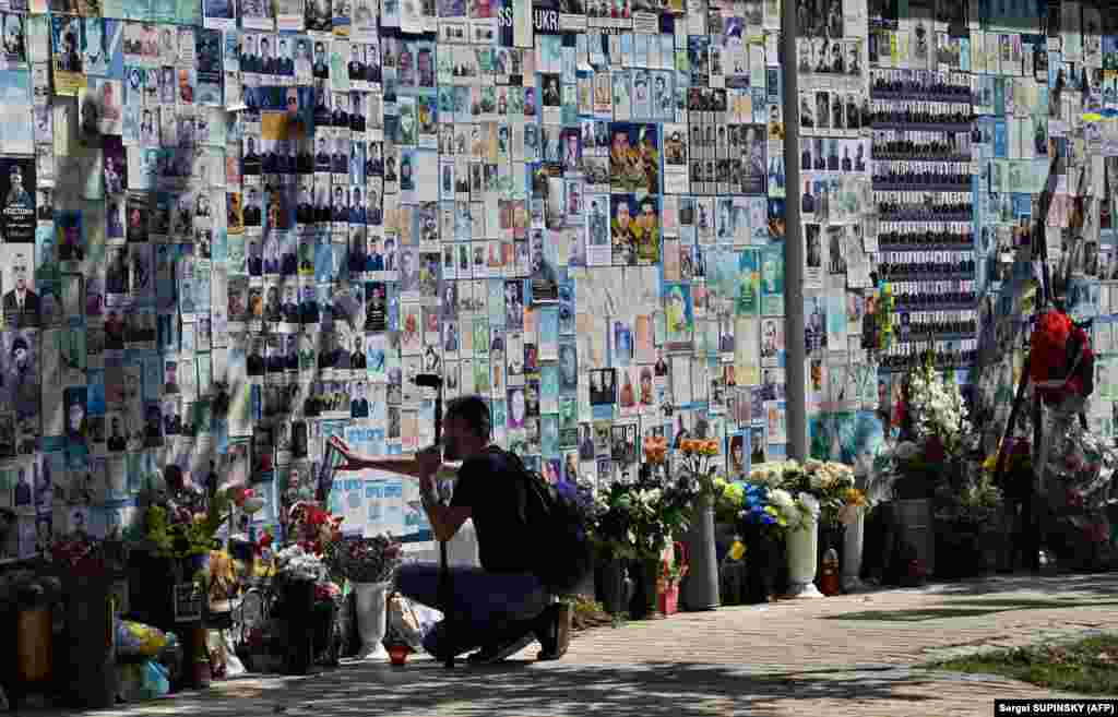 A wounded Ukrainian serviceman looks for pictures of his fallen comrades on the Memory Wall of Fallen Defenders of Ukraine in Kyiv.&nbsp;