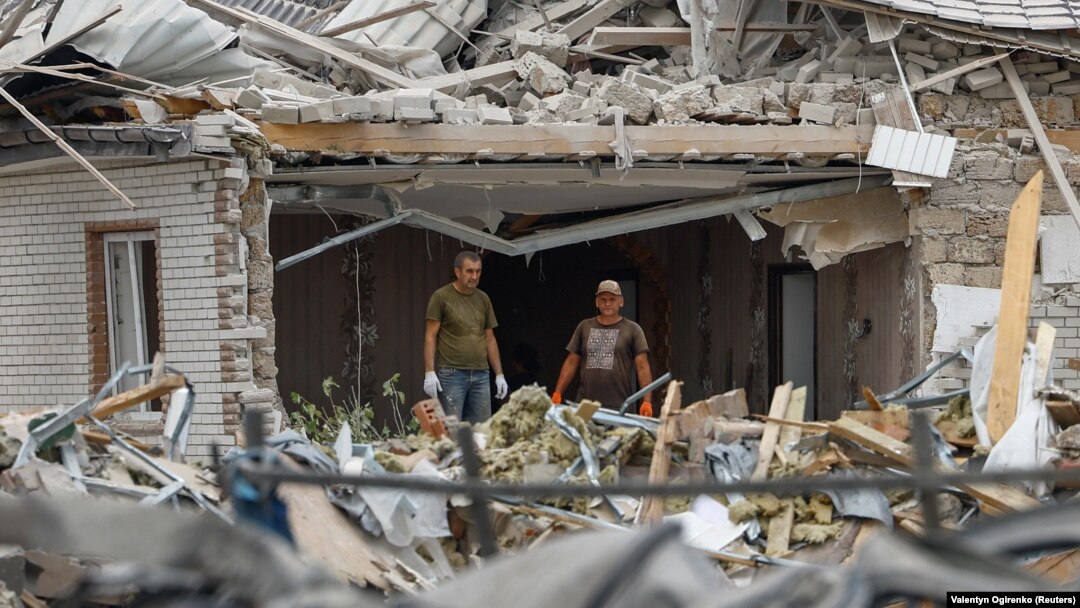 Localnicii stau în interiorul unei clădiri rezidențiale grav avariate în timpul unui atac cu rachete rusești în satul Rojivka din regiunea Kiev. 11 august 2024.
