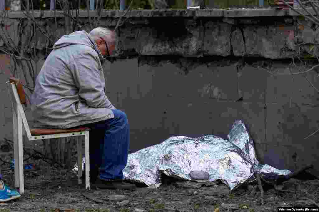 Маж седи покрај телото на неговата внука која беше убиена за време на ракетниот напад.
