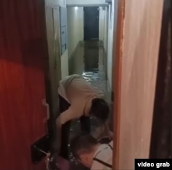 Жители дома пытаются вычерпать воду из коридора в подъезде