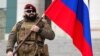 Чеченский военнослужащий с российским флагом, иллюстративная фотография
