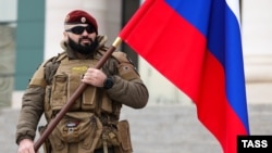 Чеченский военнослужащий с российским флагом, иллюстративная фотография