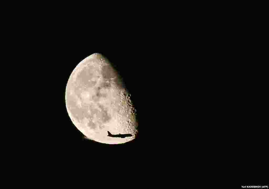 Silueta e një aeroplani shihet përballë Hënës, në qiellin mbi Moskë.