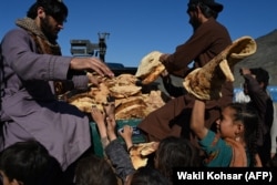 Afghan children receive bread from a local charity at a makeshift camp upon their arrival from Pakistan, near the Torkham border crossing in Nangarhar Province on November 12.