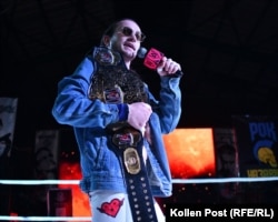 Holding a microphone and his championship belt, Hantry berates the audience at a wrestling event in Kyiv.