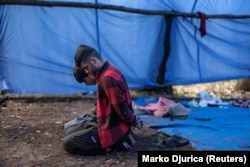 Detained migrants sit on their knees with cuffed hands at their makeshift camp close to the Hungarian border, near the city of Subotica, Serbia, on September 12.