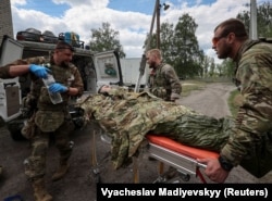 Военные медики оказывают помощь раненому украинскому военнослужащему недалеко от города Волчанск в Харьковской области, 12 мая 2024 года