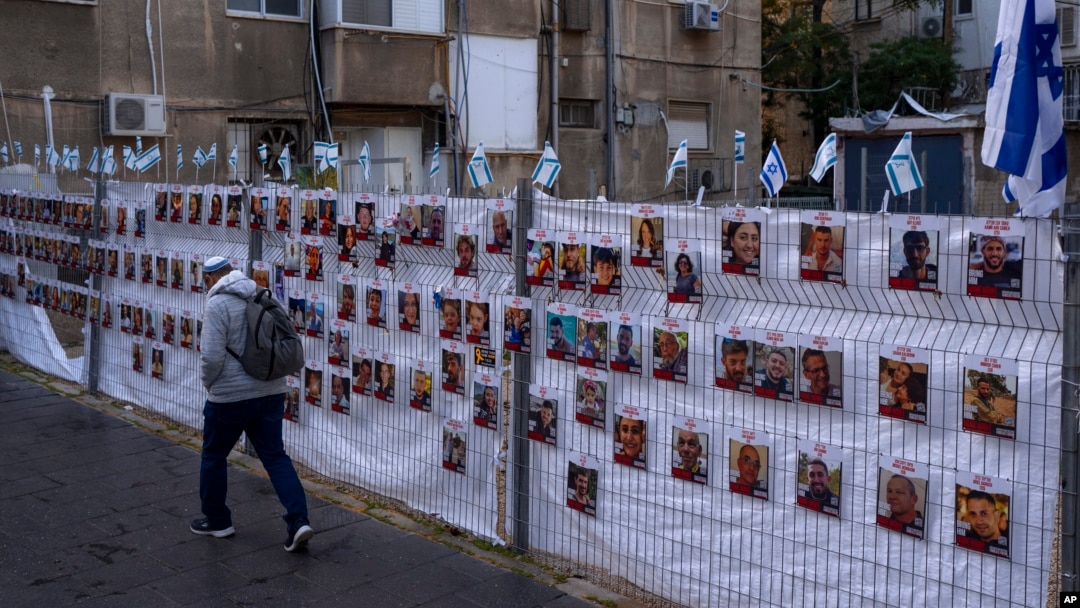  Israel - Un bărbat trece pe lângă un gard cu fotografii cu ostatici, în mare parte civili israelieni, care au fost răpiți în timpul atacului fără precedent al Hamas din 7 octombrie asupra Israelului, în Ramat Gan, Israel, miercuri, 22 noiembrie 2023.