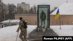 Un militar ucrainean în cârje se uită la un monument comemorativ, recent instalat pentru a aduce un omagiu soldatului ucrainean ucis Olexandr Mațievski, în Kiev, 7 decembrie 2023.