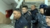 Azamat Estebesov (second from left) is accompanied by police at a court in Sokuluk on January 26. 